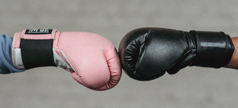 Two people bumping each others' hands while wearing boxing gloves during personal training uae