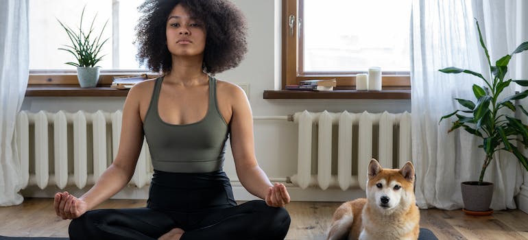 a woman with her dog doing yoga with a personal yoga instructor UAE