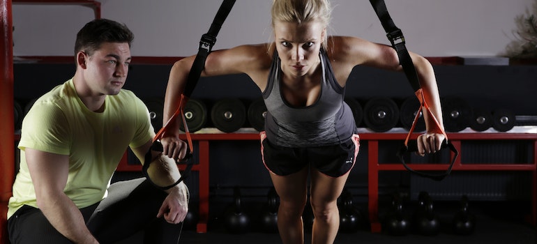 A woman exercising on TRX with her personal trainer