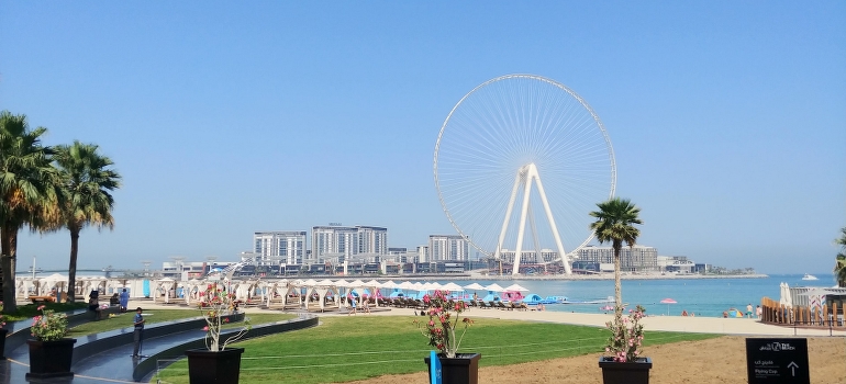 A Ferris wheel in the middle of a beach, Dubai with hotels that offer personal fitness trainer UAE in the background
