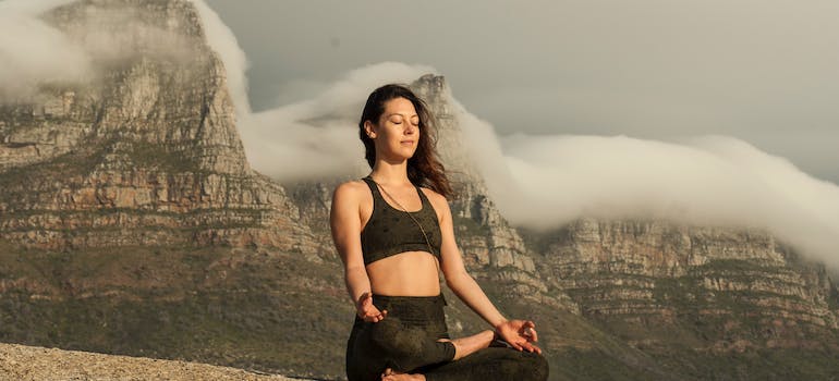 A woman meditating at the top of a mountain. 