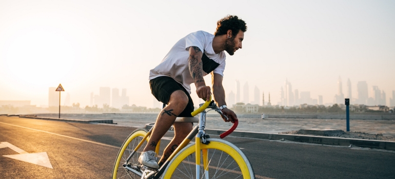 A man riding bicycle on road in Dubai while thinking of personal training for busy UAE professionals. 