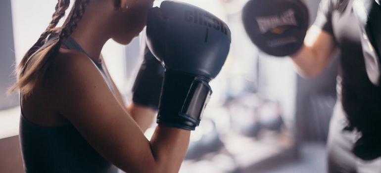 A woman wearing black boxing gloves.