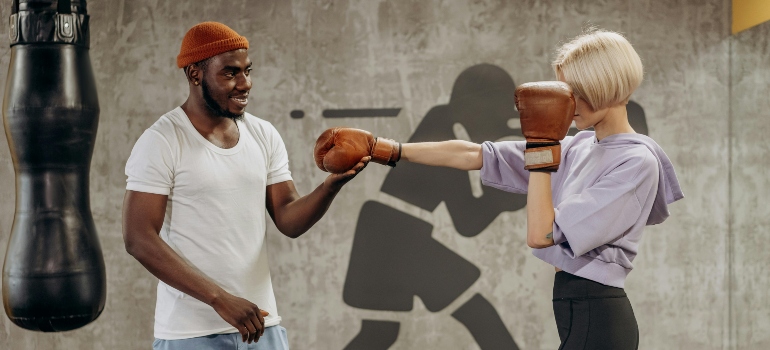 A trainer teaching a person to punch and talking about the health benefits of boxing.