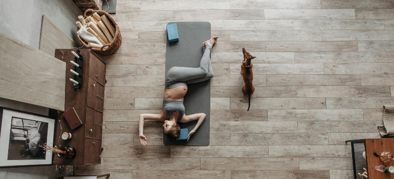 A pregnant woman doing yoga at home with her dog. 
