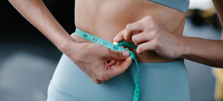 A woman measuring her waist after dealing with weight loss challenges and solutions