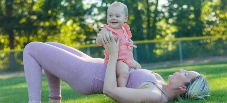 A woman working out with her baby after finding the right post-natal trainer in Abu Dhabi.