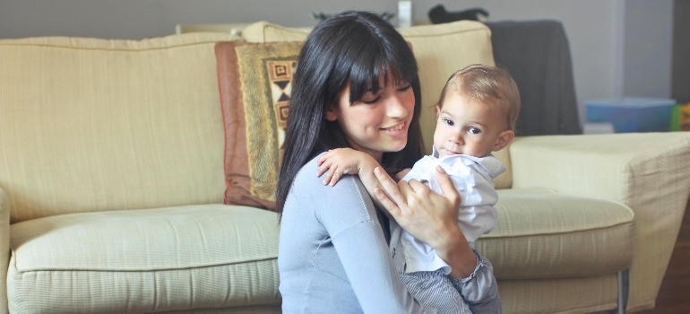a mom holding her baby thinking about the Gentle Exercise Options for Post-Natal Moms in Ajman