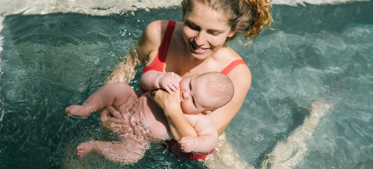 A woman swimming with her baby. 
