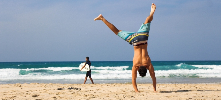 a men on a beach doing a handstand