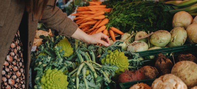 A woman picking up vegetables at a farmers' market.