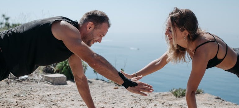 a man and woman exercising near the beach