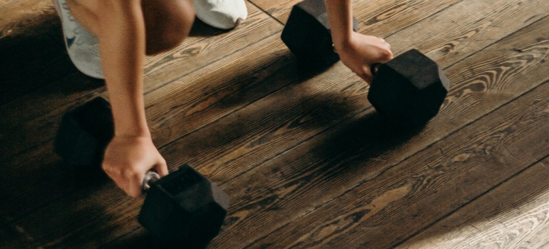 A person in white shorts and black shoes standing on brown wooden floor 