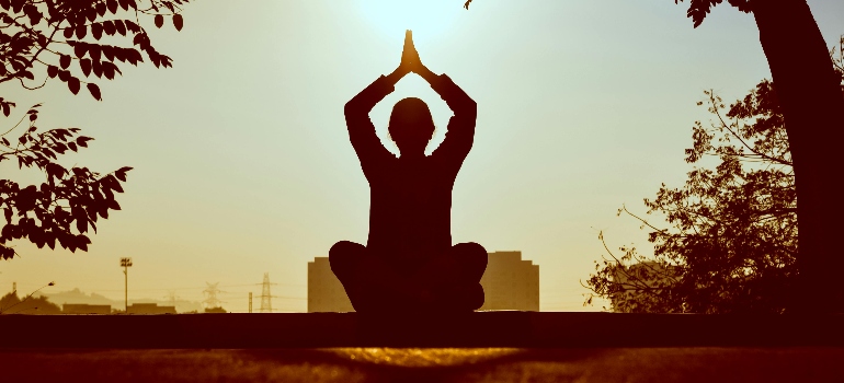 a woman at sunrise doing various types of yoga offered in Ajman