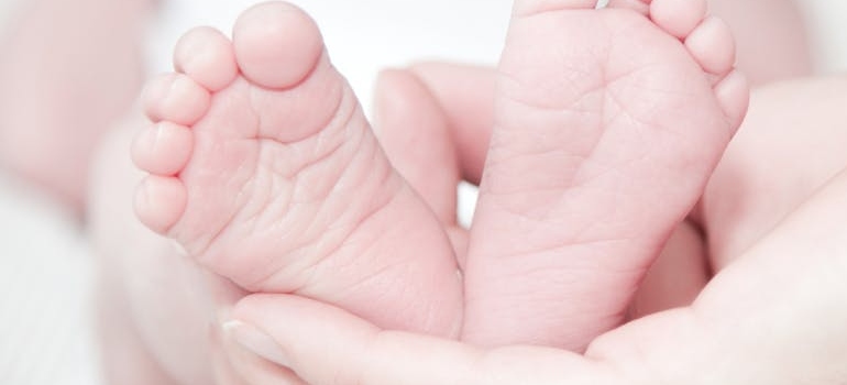 a woman holding her baby's feet after experiencing some of the benefits of post-natal yoga