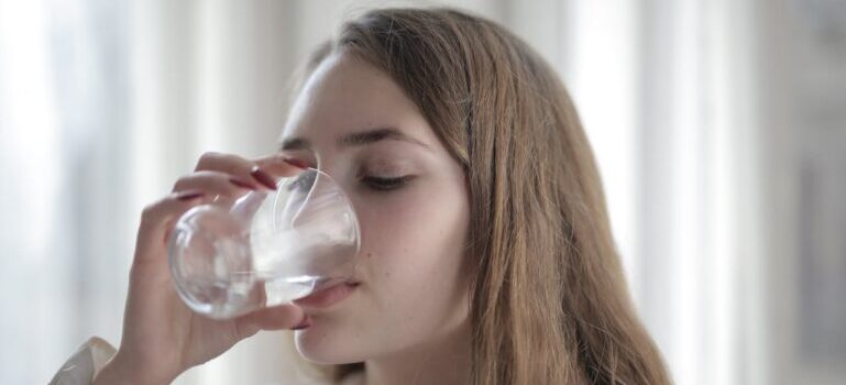 A woman drinking water after understanding the role of hydration in weight loss for Dubai residents 