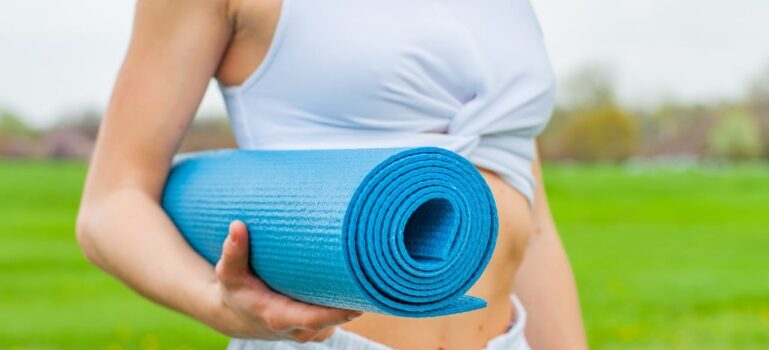 A woman holding a yoga mat