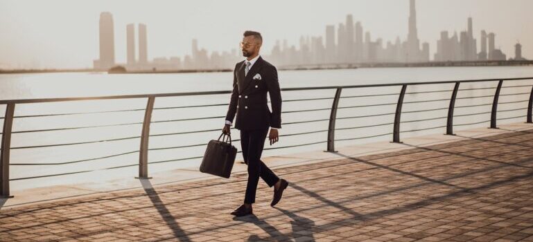 A man walking, holding a bag and thinking about yoga for busy professionals in Dubai