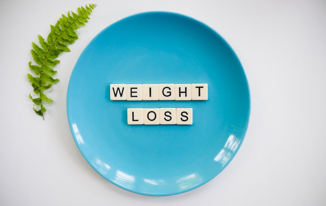 Weight loss spelled with scrabble tiles on a blue plate, representing How to Stay Motivated on Your Weight Loss Journey in Dubai
