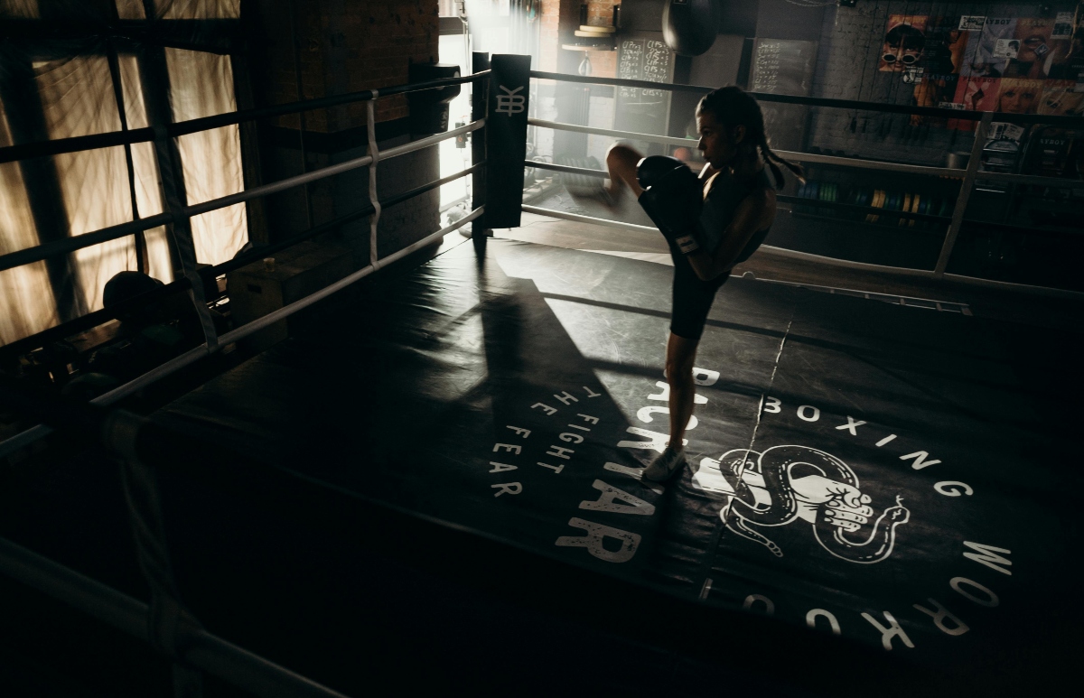 A woman kicking a bag while boxing.