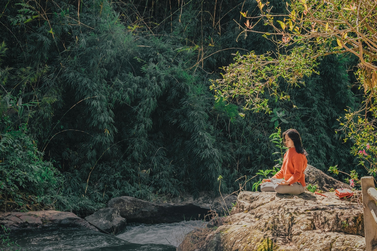 A woman meditating in the woods.