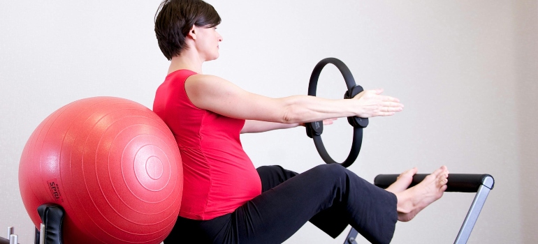 A woman in red shirt sitting on fitness equipment 